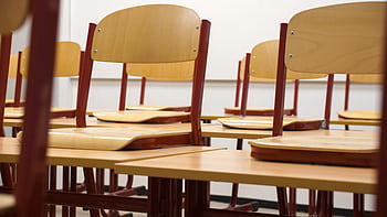 A modern and empty classroom featuring wooden chairs and desks with a focus on education and learning spaces. HD wallpaper
