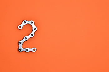 Metal chain forming the number 2 on a bright orange background, perfect for design projects. HD wallpaper