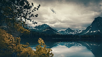 Captivating mountain landscape with dramatic clouds and a serene reflective lake, showcasing nature's beauty. HD wallpaper