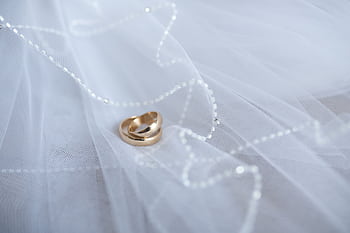 Beautiful gold wedding rings resting on soft white tulle with delicate beaded details, symbolizing love and commitment. HD wallpaper