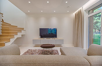 Contemporary living room with stylish sofa, TV, and staircase, offering a cozy interior design setting. HD wallpaper