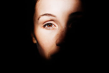 A striking portrait highlighting a woman's eye with dramatic light and shadow play. HD wallpaper