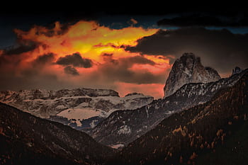 A stunning dramatic sunset casts fiery hues over a snow-capped mountain range. HD wallpaper