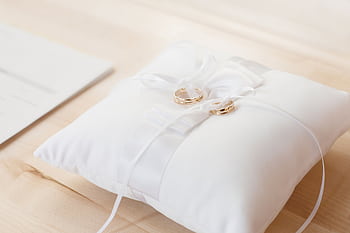 Gold wedding rings elegantly displayed on a white satin pillow, symbolizing love and commitment. HD wallpaper