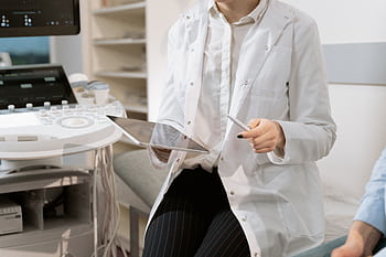 Doctor holding a tablet in a modern medical office during a patient consultation. HD wallpaper