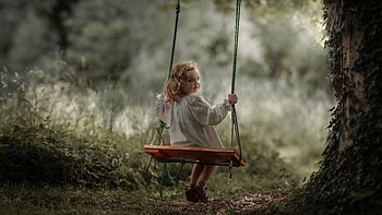 Cute Little Girl Is Sitting On Swing Looking Back Wearing White Dress In Blur Background Cute HD wallpaper