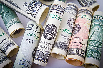 Close-up of rolled US dollar bills symbolizing wealth, financial success, and currency. HD wallpaper