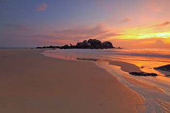 A tranquil beach sunset with vibrant skies reflecting on the sandy shore and gentle waves. HD wallpaper
