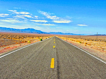 A long straight road in the Nevada desert under a blue sky, perfect for travel and adventure. HD wallpaper