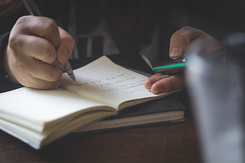 Detail shot of adult hands writing in a notebook, possibly researching or studying. HD wallpaper