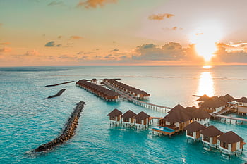 A breathtaking view of luxurious overwater villas in the Maldives at sunset. HD wallpaper