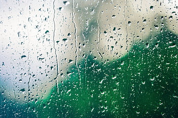 Raindrops on a glass window create a soothing pattern with a blurred green backdrop. HD wallpaper