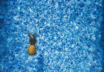 Vibrant pineapple floating in a blue mosaic tile pool, capturing summer vibes and tropical aesthetics. HD wallpaper