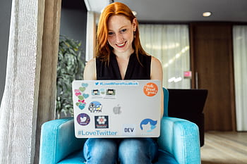 Smiling woman engaged in remote work on a laptop at home office setting. HD wallpaper