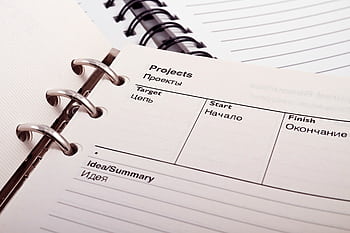 Open planner displaying project schedule with Russian-English text, ideal for office or educational content. HD wallpaper