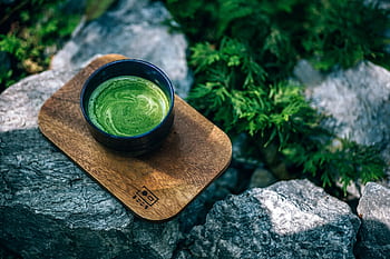 Top view of a green matcha tea served on a wooden tray outdoors, surrounded by rocks. HD wallpaper