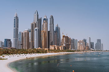 A breathtaking view of Dubai's iconic skyline with modern skyscrapers against a clear blue sky. HD wallpaper