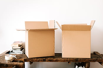 Open cardboard boxes and books on a rustic table, ideal for moving and packing themes. HD wallpaper