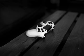 Black and white of a gaming controller on a wooden table, perfect for gaming or tech themes. HD wallpaper