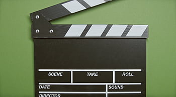 A classic film clapperboard on a green surface, essential for movie scenes. HD wallpaper