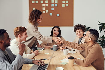 Diverse team collaborating in a meeting, showcasing teamwork and cooperation in a modern workplace. HD wallpaper