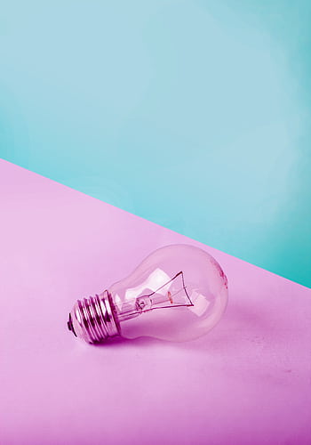 A clear lightbulb on a pastel pink and blue background, showcasing contrast and simplicity. HD phone wallpaper