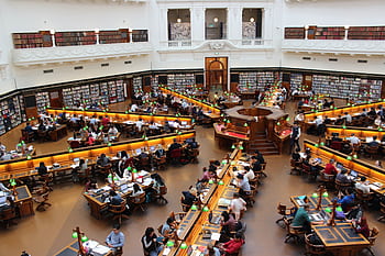 Aerial view of a bustling study hall in a university library with students studying. HD wallpaper