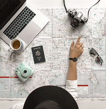 Hand on map with camera, passport, laptop, and coffee, perfect for travel planning inspiration. HD phone wallpaper