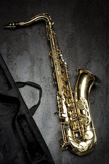 A sleek golden saxo laid on a textured dark background, showcasing its intricate design HD phone wallpaper