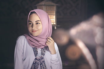 A serene portrait of a woman wearing a pink hijab, exuding grace and elegance. HD wallpaper