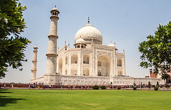 Iconic Taj Mahal showcasing its white marble beauty and lush gardens on a sunny day. HD wallpaper