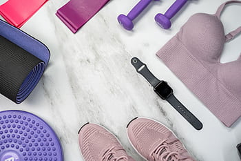 Flat lay of fitness gear including yoga mat, dumbbells, and smartwatch on a marble surface. HD wallpaper