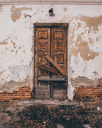 Rustic wooden door on a cracked wall of an abandoned building, showcasing decay and vintage charm. HD phone wallpaper