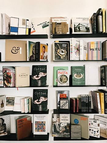 A beautifully curated bookshelf displaying a diverse collection of books in a modern library setting. HD phone wallpaper