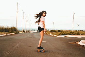 Enjoy a moment of dom as a young woman skateboards down an empty road. HD wallpaper