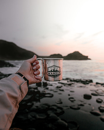 Water, Sunset, Rocks, Hand, Miscellanea, Miscellaneous, Cup, Mug HD phone wallpaper