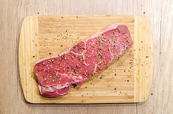 Raw beef steak seasoned with spices on a wooden chopping board. Perfect for cooking enthusiasts. HD wallpaper