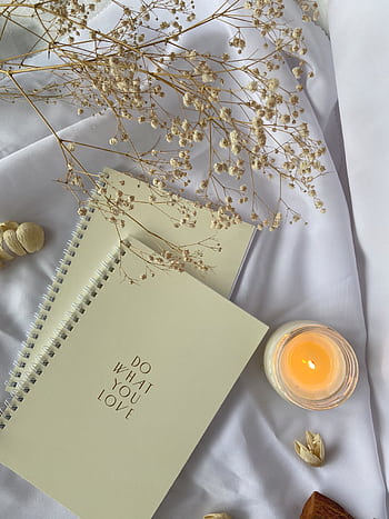 Cozy flat lay featuring an inspirational notepad, candle, and dried flowers for a serene workspace atmosphere. HD phone wallpaper