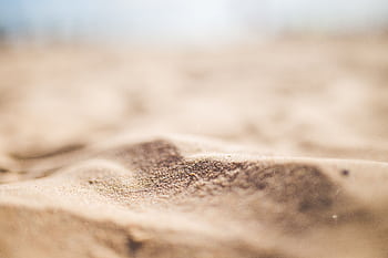 A detailed macro shot highlighting the texture and color of sandy dunes at a beach. HD wallpaper