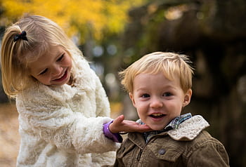 A delightful of two children enjoying a playful moment outdoors in fall. HD wallpaper