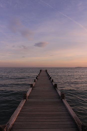 Serene sunset view from a wooden dock over calm waters, perfect for relaxation. HD phone wallpaper