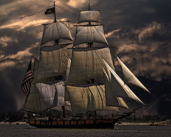 A majestic sailing ship with white sails against a dark, stormy sky, evoking a sense of adventure. HD wallpaper