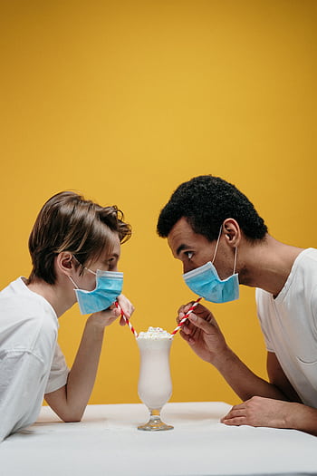Couple sharing a milkshake while wearing masks, symbolizing love during pandemic. HD phone wallpaper