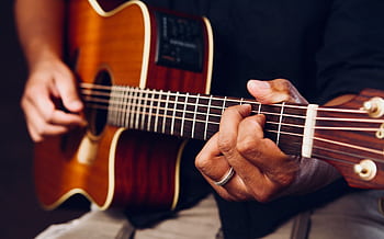Hands playing an acoustic guitar, showcasing chords and frets up close. HD wallpaper