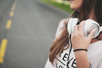 Close-up of a woman outdoors holding heads, enjoying music on a quiet road. HD wallpaper