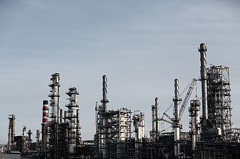 Skyline view of an industrial factory with tall chimneys against a clear sky. HD wallpaper