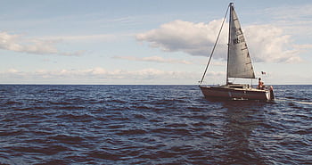 A sailboat sails across the open Mediterranean sea under a clear sky, capturing nautical adventure. HD wallpaper