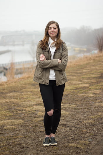 Young woman in casual attire standing by a foggy riverbank, embodying modern fashion and lifestyle. HD phone wallpaper