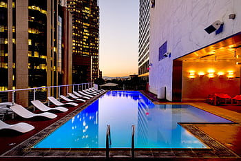 Elegant rooftop pool with cityscape backdrop at sunset, reflecting urban luxury. HD wallpaper