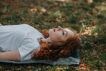 Adult woman with red hair resting peacefully outdoors on a sunny day, surrounded by nature. HD wallpaper